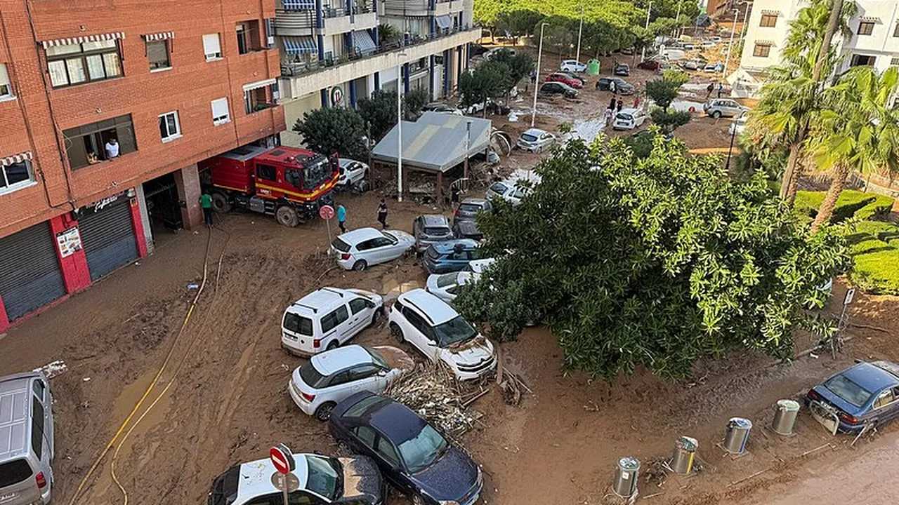 Vehículos dañados y equipo de emergencia en una zona afectada por la DANA en Catarroja, Valencia.